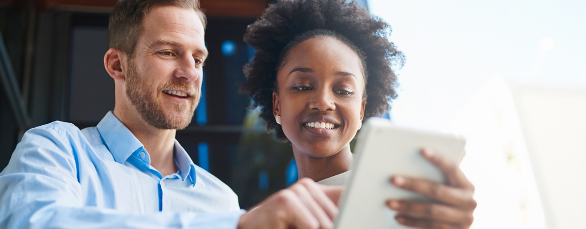 white man and black woman look at an ipad