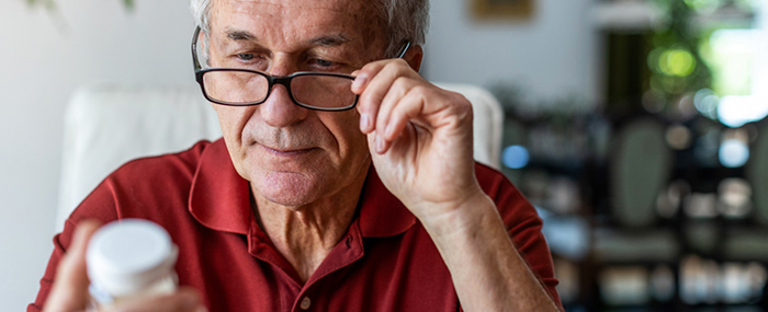 elderly man looks at prescription bottle