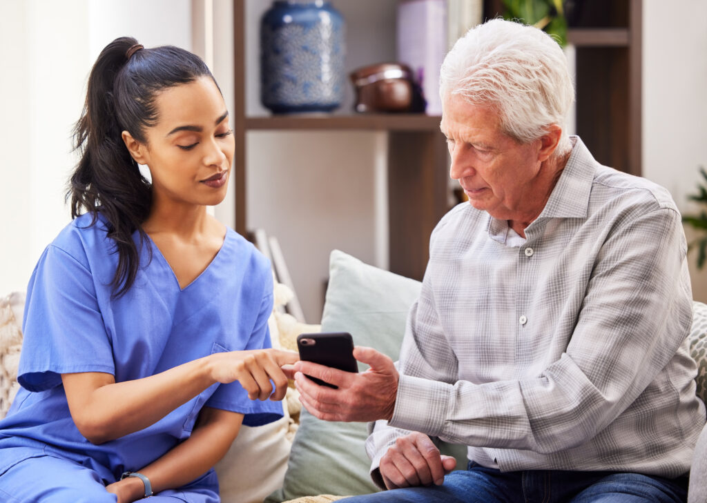 heathcare professional shows elderly male how to use smart phone