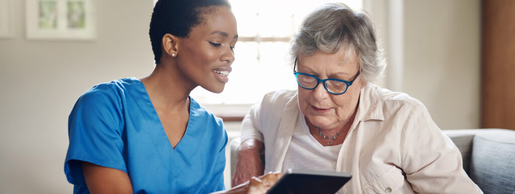 Shot of a senior woman using a digital tablet with a nurse on the sofa at home